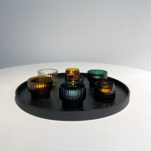 Collection of XLBoom Serve trays in sleek black finish, displayed in various shapes and sizes—round, rectangular, and square—on a smooth concrete floor. Each tray features a subtle wood grain texture and raised edges, showcasing the minimalist design and versatility of the Serve series.