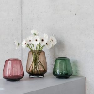 XLBoom Kuro Smooth Vases in moss, smoke, and plum glass with white flowers on a concrete pedestal