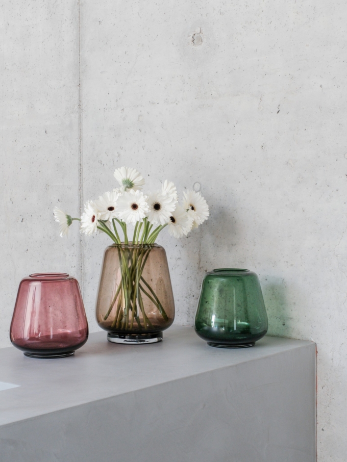 XLBoom Kuro Smooth Vases in moss, smoke, and plum glass with white flowers on a concrete pedestal