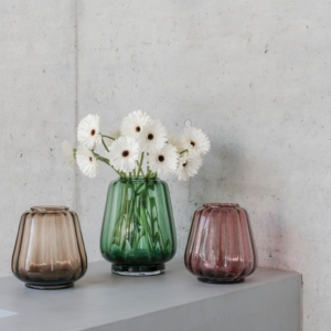 XLBoom Kuro Wave Vases in smoke, moss, and blush glass with white flowers on a concrete pedestal