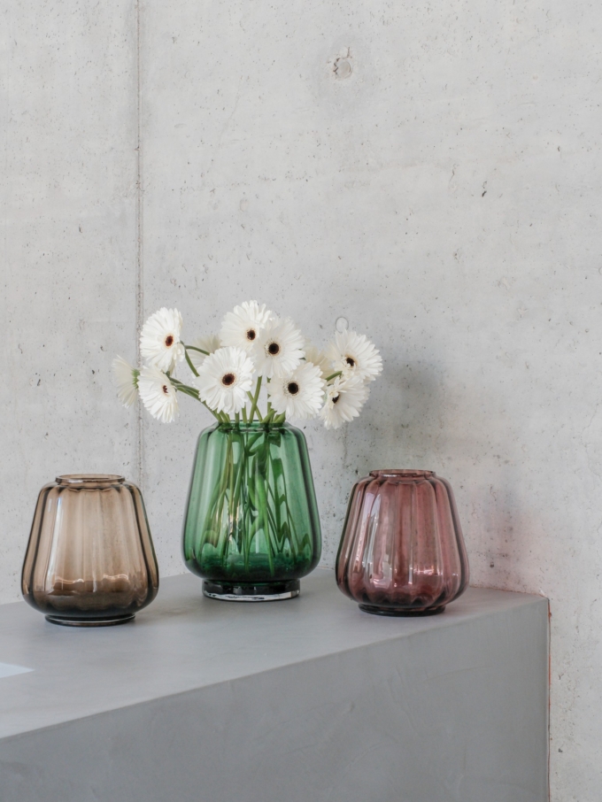 XLBoom Kuro Wave Vases in smoke, moss, and blush glass with white flowers on a concrete pedestal
