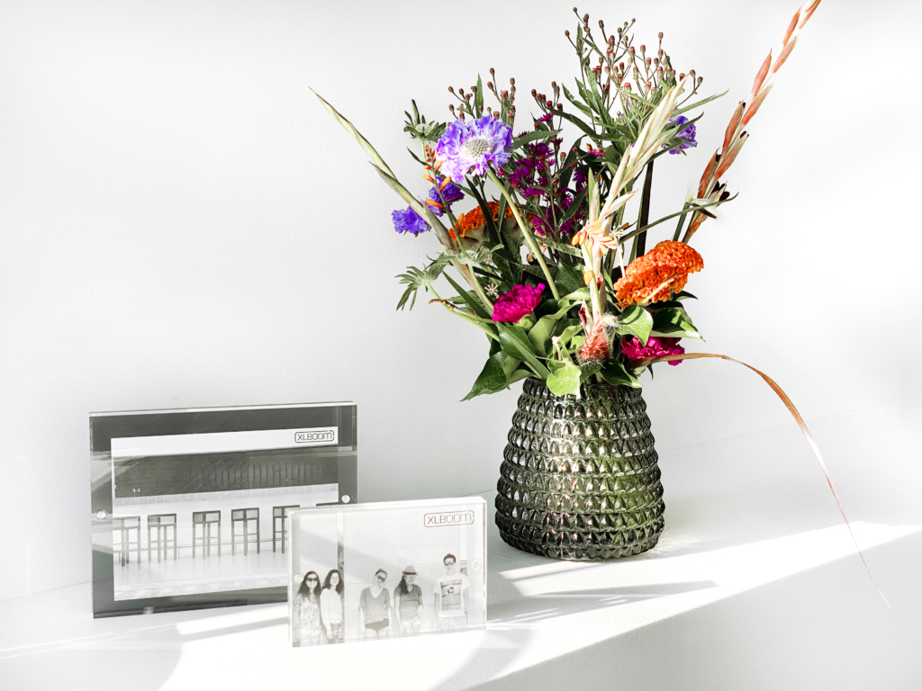 XLBoom Dim Scale Vase Small in smoke grey glass with colorful flowers beside Acrylic Magnetic Frames in dark grey